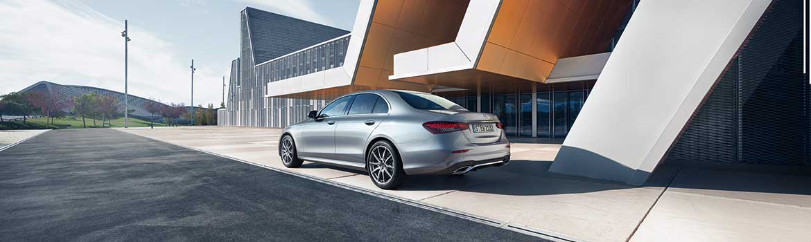 Die Mercedes E-Klasse Limousine parkt vor einem modernen Gebäude.