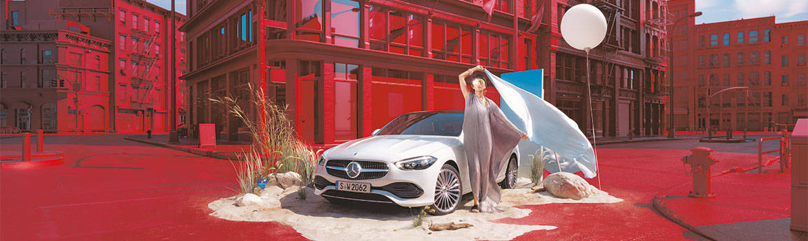 Mercedes-Benz-Werbekampagne. Weisser Mercedes vor rotem Hintergrundgebäuden