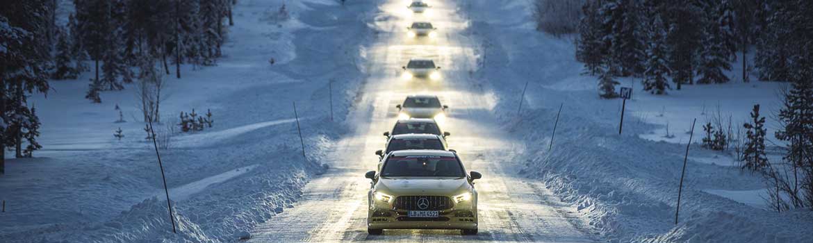 Ein Auto fährt mit eingeschaltetem Licht eine verschneite Straße entlang.